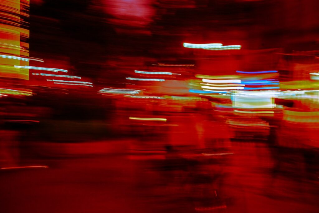 Long-exposure photograph of a single streak of light moving purposefully through the chaotic, blurred light trails of a bu...