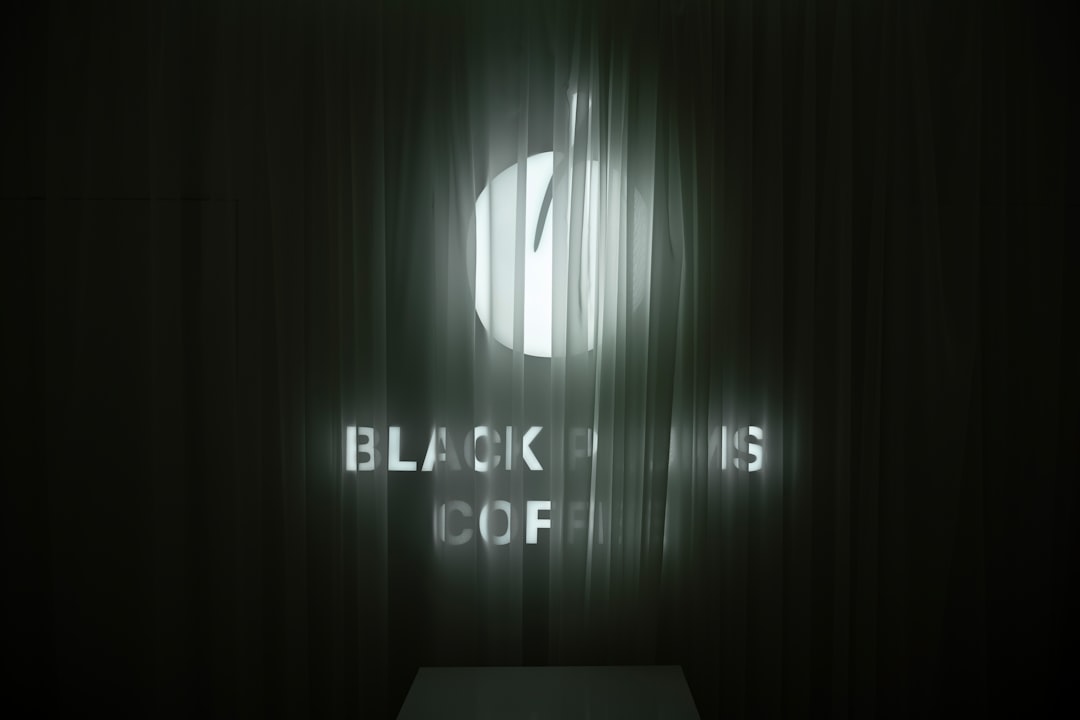A minimalist image of a black cube on a dark surface with a single, bright beam of light emanating from it, representing hidden business intelligence being revealed.