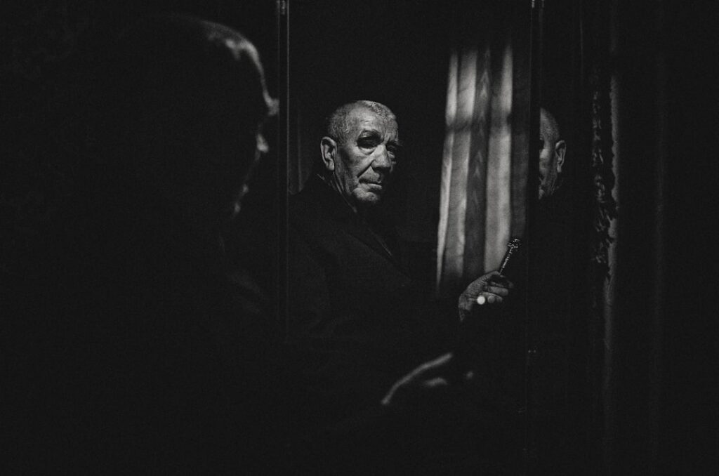 Person's face is reflected infinitely in a series of mirrors, creating a disorienting echo chamber effect in a dark, moody...