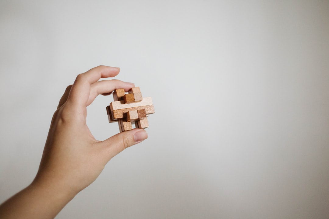 A person's hands carefully and precisely arranging minimalist wooden blocks on a clean white surface, representing the strategic construction of a brand's core concepts.