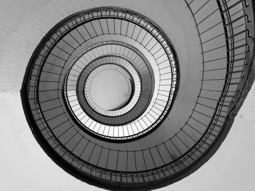 A minimalist, top-down view of a clean architectural spiral staircase, representing a continuous and efficient decision-making cycle.