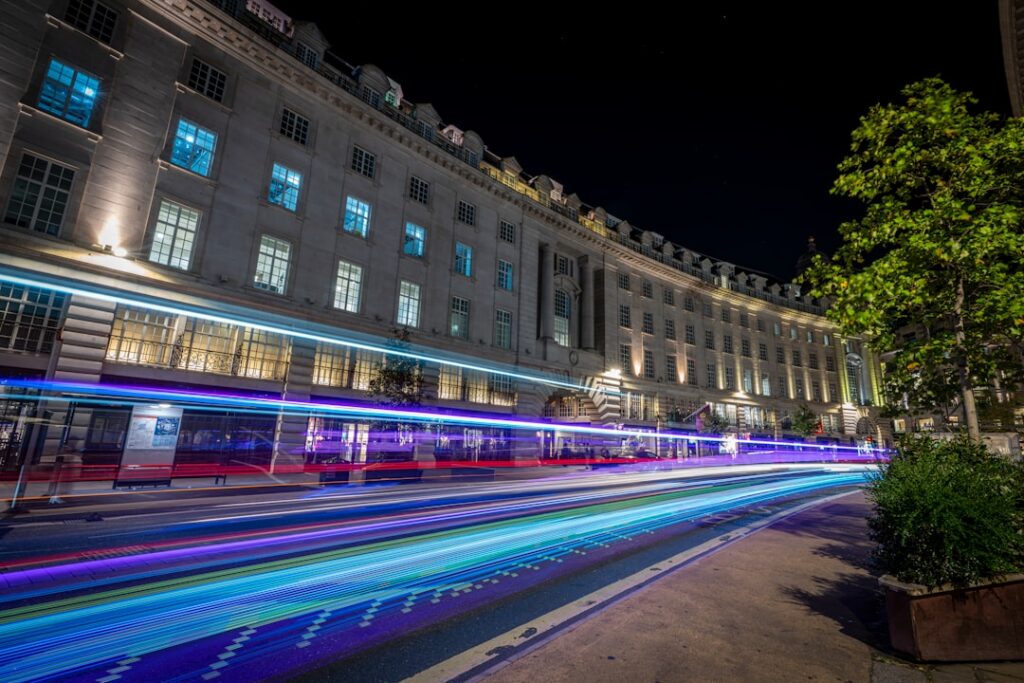 Modern city street at night with vibrant, blurred light trails from cars, visually representing speed and algorithmic time...