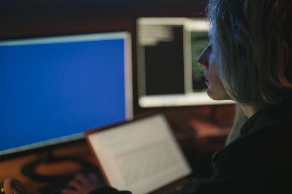 A business professional in a modern, dark office looking with concern at a brightly glowing computer screen, symbolizing the business risks of AI.
