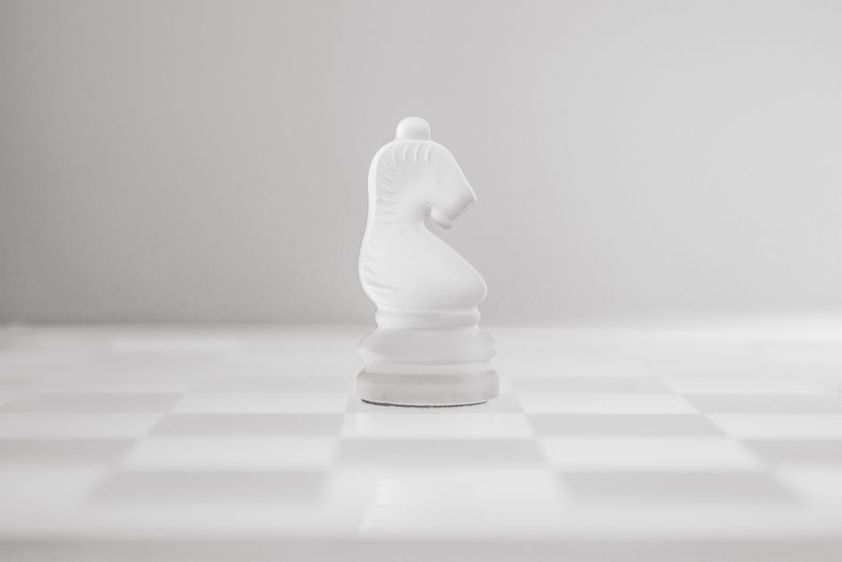 A minimalist, high-contrast photo of a chess board with a single, unique piece in sharp focus against a row of identical pawns, representing bespoke strategy versus generic AI tools.