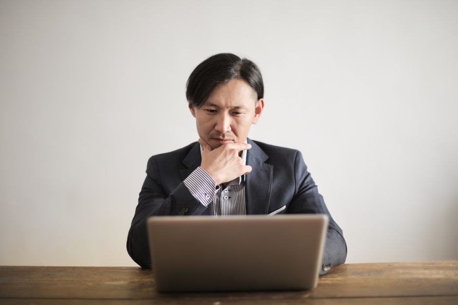 A professional person with a thoughtful, nuanced expression looking at a laptop screen in a bright, modern setting, illustrating unspoken customer intent.
